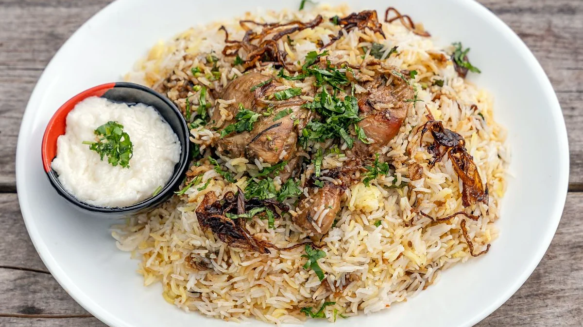 Malabar Dum Biryani with fried onions, herbs and a side of raita